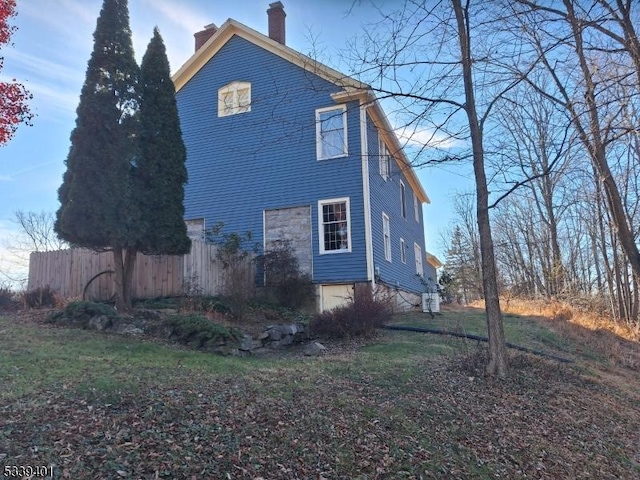 view of side of home featuring a chimney and fence