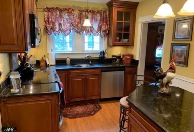 kitchen with dishwasher, glass insert cabinets, decorative light fixtures, light wood-type flooring, and a sink