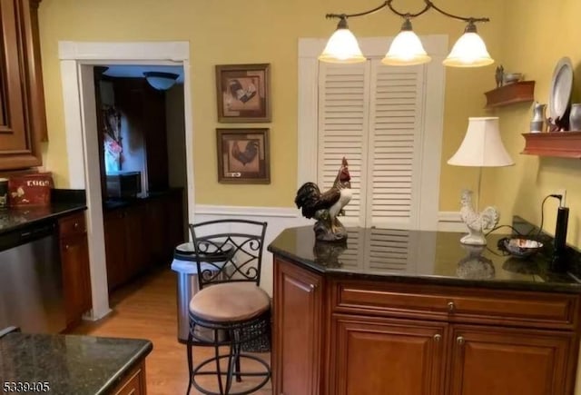 bar with light wood finished floors, hanging light fixtures, and stainless steel dishwasher