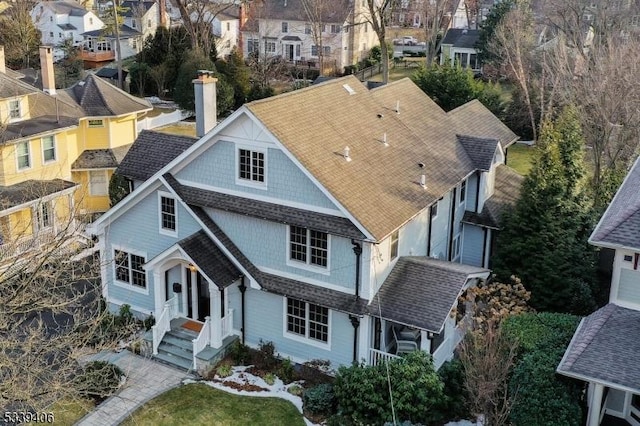 view of front of property featuring a shingled roof, a chimney, and a residential view