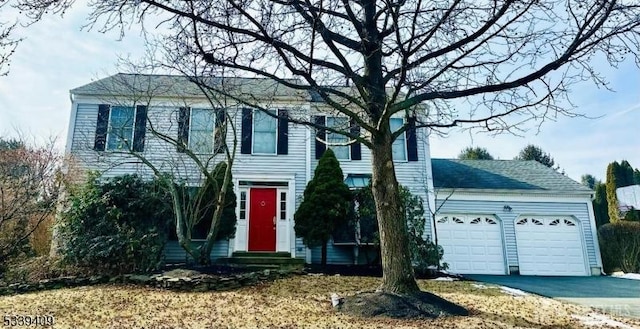 colonial house with entry steps, driveway, and an attached garage