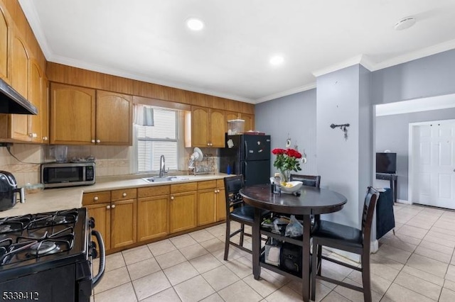 kitchen with a sink, light countertops, brown cabinets, black appliances, and crown molding