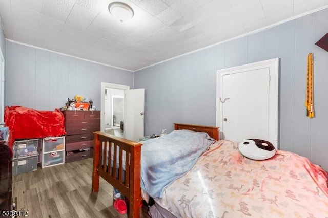 bedroom with wood finished floors and crown molding