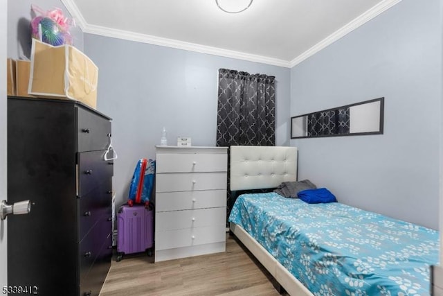 bedroom with ornamental molding and wood finished floors