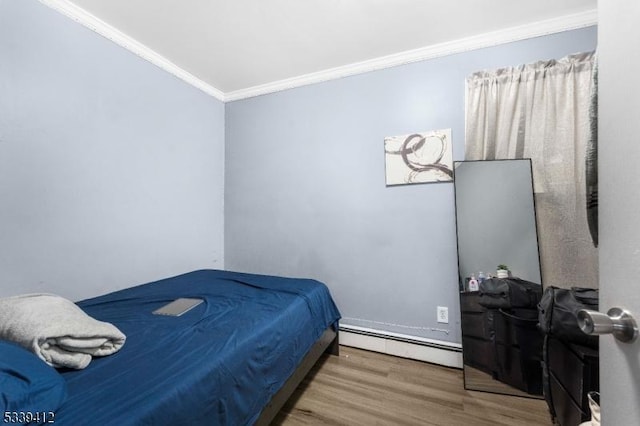 bedroom featuring baseboard heating, wood finished floors, and crown molding