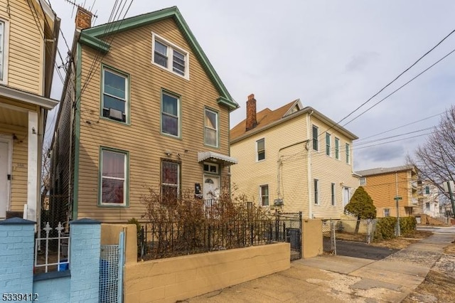 exterior space with a fenced front yard, a gate, and a chimney