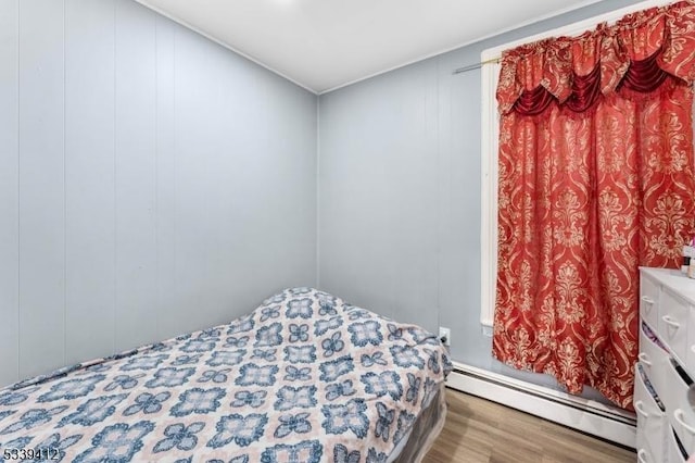 bedroom featuring baseboard heating and wood finished floors