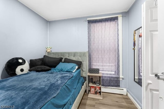 bedroom featuring baseboard heating and wood finished floors