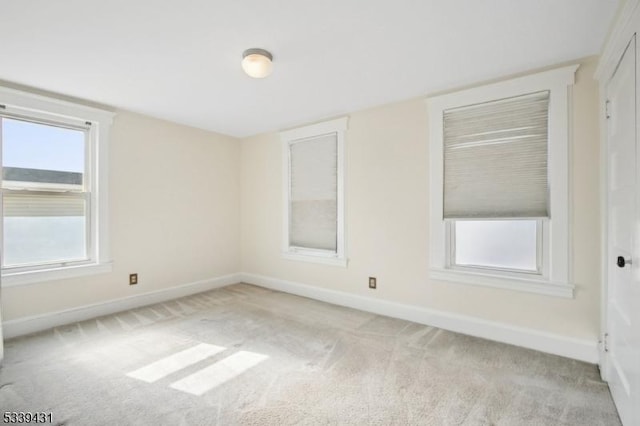 empty room featuring light carpet and baseboards