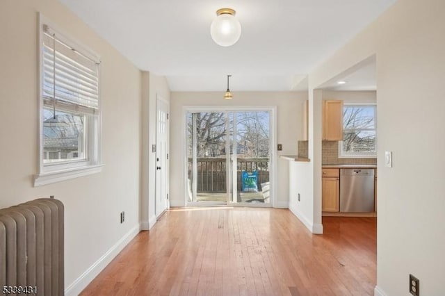 doorway to outside with light wood-style floors, radiator heating unit, and baseboards