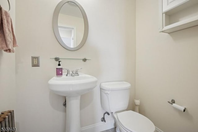 bathroom with toilet, radiator heating unit, and baseboards