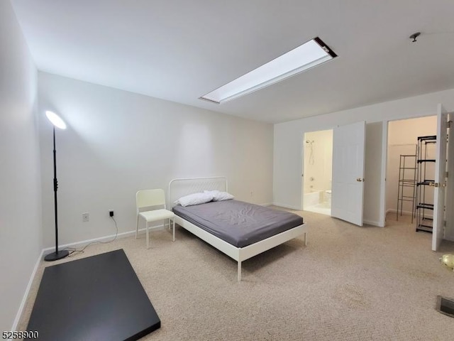 bedroom with light colored carpet, ensuite bath, and baseboards