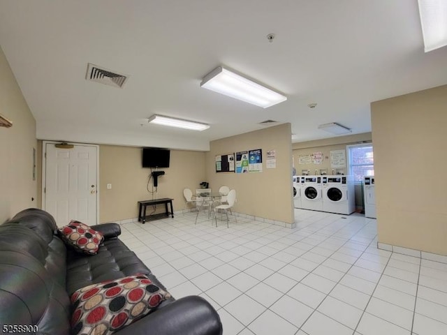 living room with visible vents, washer and clothes dryer, and light tile patterned flooring