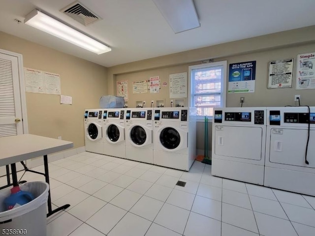 community laundry room with light tile patterned floors, visible vents, and washer and clothes dryer