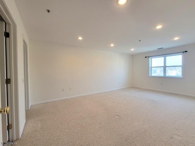 empty room with recessed lighting, light carpet, visible vents, and baseboards