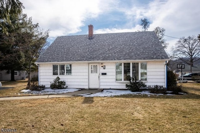 view of front facade featuring a shingled roof, a chimney, and a front lawn