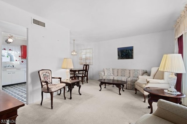 living area featuring light carpet, visible vents, and a chandelier