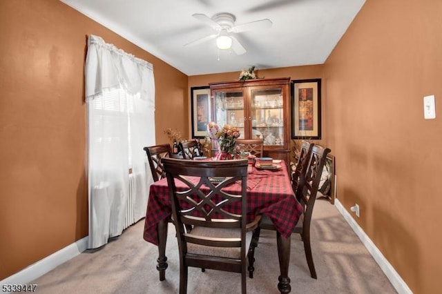 dining space featuring ceiling fan, baseboards, and light colored carpet