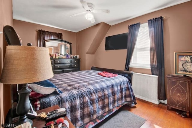 bedroom with radiator, light wood finished floors, and ceiling fan