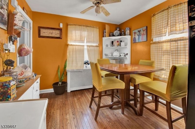 dining space with baseboards, a ceiling fan, and wood finished floors