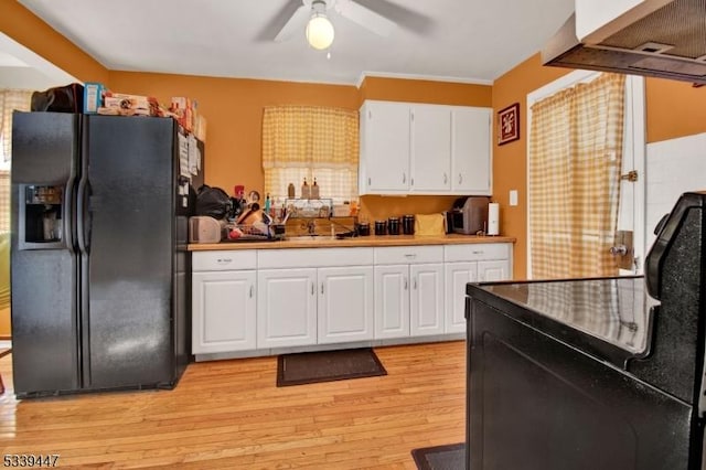 kitchen with black fridge with ice dispenser, ceiling fan, light wood-style flooring, ventilation hood, and white cabinetry