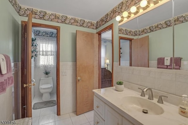 bathroom with vanity, tile patterned flooring, wainscoting, tile walls, and toilet