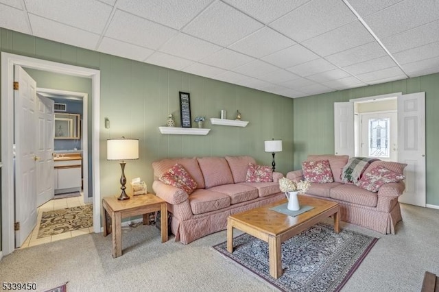 carpeted living area with a drop ceiling