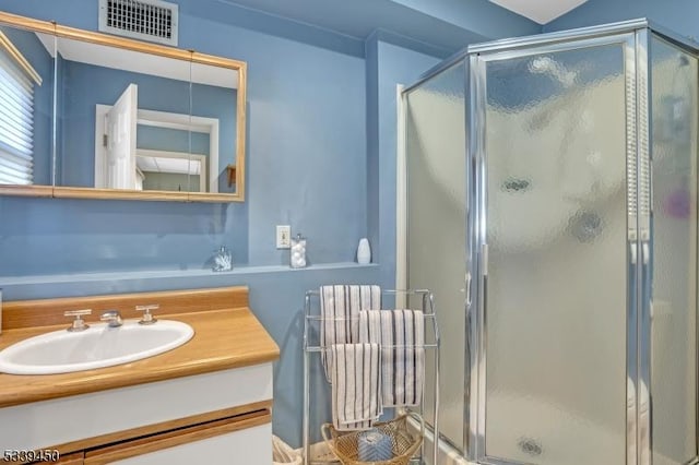 full bath with visible vents, vanity, and a shower stall