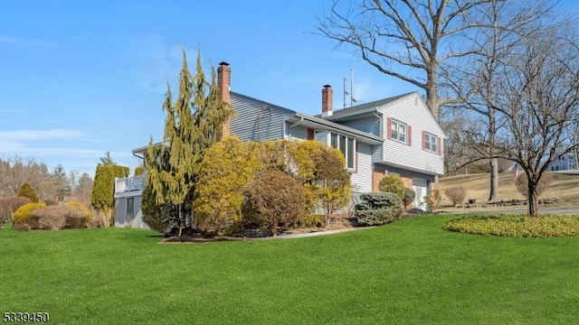 exterior space with a front lawn, an attached garage, and a chimney