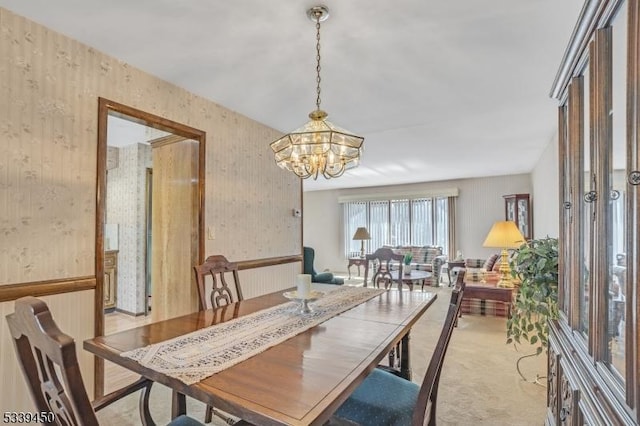 dining room featuring wallpapered walls, an inviting chandelier, and light carpet