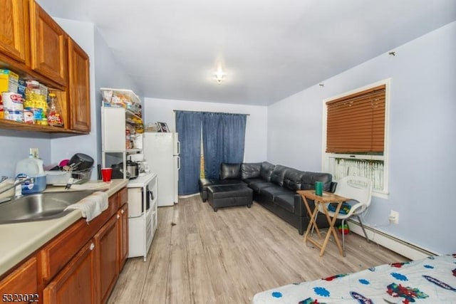 kitchen featuring light countertops, light wood-type flooring, a baseboard radiator, and a sink