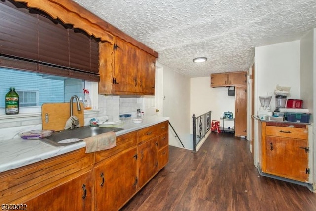 kitchen with dark wood-style flooring, brown cabinets, tasteful backsplash, light countertops, and a sink