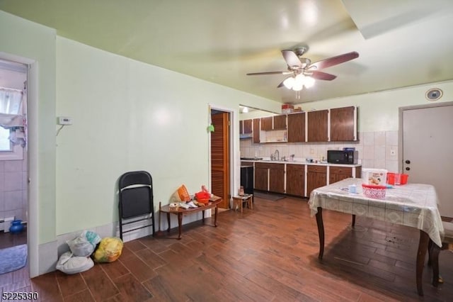 kitchen featuring black microwave, dark wood-style flooring, a ceiling fan, tile counters, and tasteful backsplash