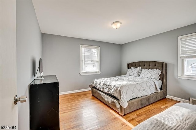 bedroom featuring multiple windows, baseboards, and wood finished floors