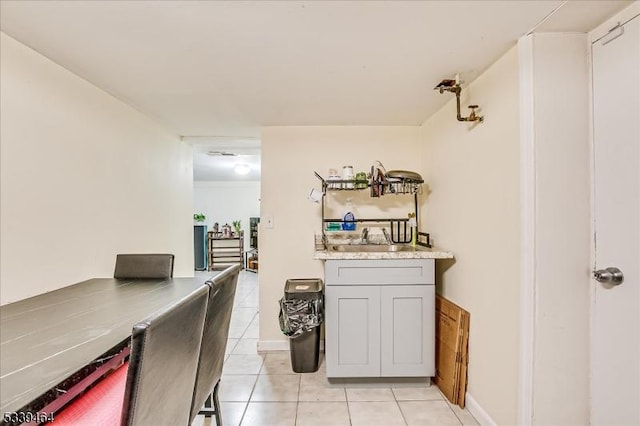 bar featuring light tile patterned floors, baseboards, and a sink