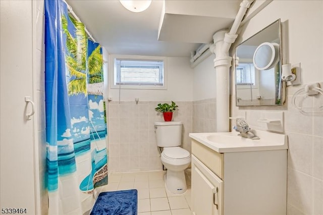 bathroom with tile patterned flooring, toilet, a wainscoted wall, vanity, and tile walls