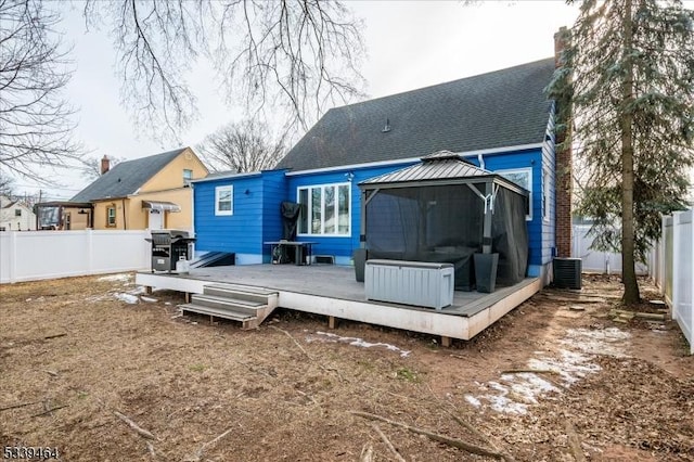 rear view of house with a fenced backyard, a wooden deck, a gazebo, and roof with shingles