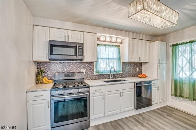 kitchen featuring stainless steel appliances, a sink, and white cabinetry