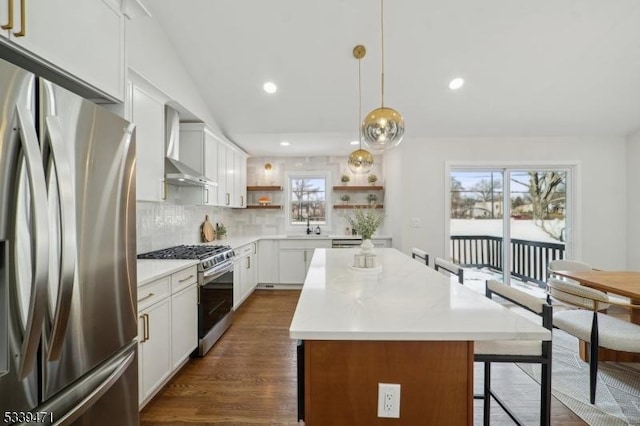 kitchen featuring a center island, open shelves, appliances with stainless steel finishes, white cabinets, and wall chimney exhaust hood