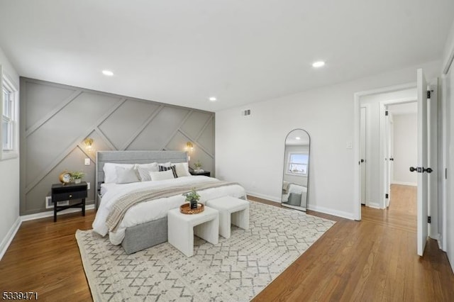 bedroom with recessed lighting, visible vents, baseboards, and wood finished floors