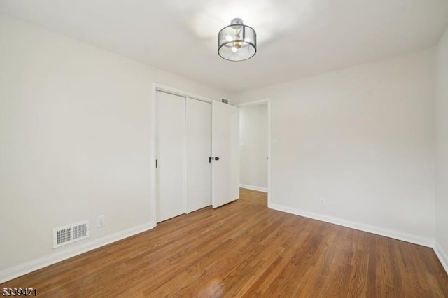 spare room with visible vents, baseboards, and wood finished floors