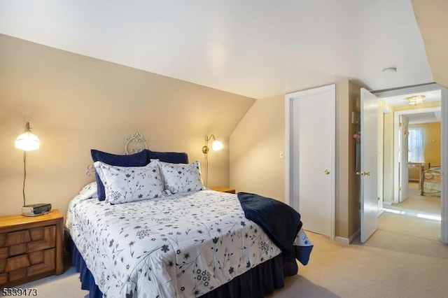 bedroom with lofted ceiling and light colored carpet