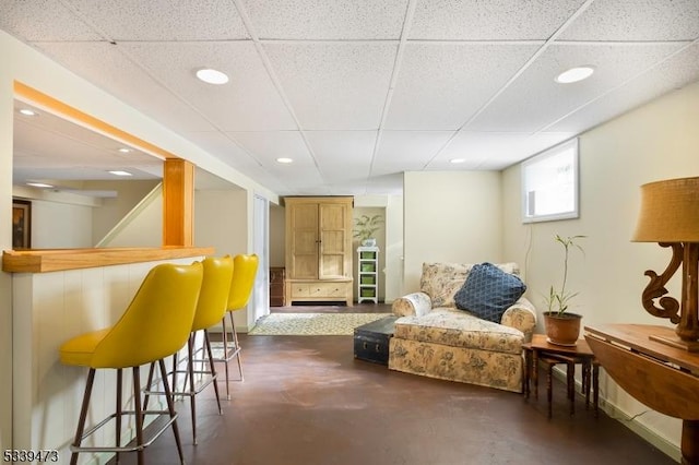 interior space featuring a paneled ceiling, finished concrete flooring, a dry bar, and recessed lighting