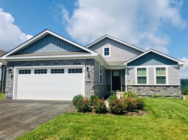 craftsman house featuring an attached garage, board and batten siding, a front yard, stone siding, and driveway