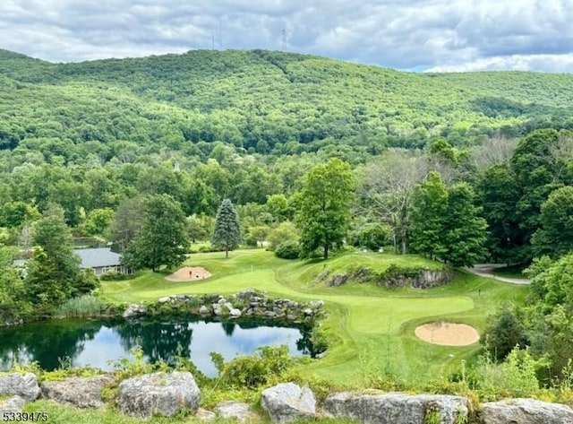 drone / aerial view featuring view of golf course, a water view, and a view of trees