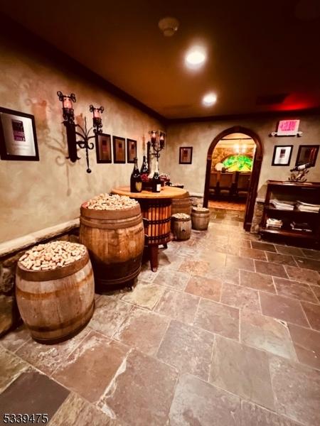 wine room featuring arched walkways, stone tile floors, and recessed lighting