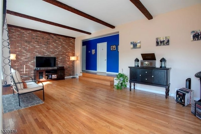 living area featuring beam ceiling, baseboards, and wood finished floors