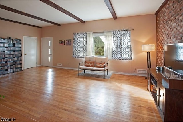 unfurnished room with visible vents, beamed ceiling, light wood-style flooring, and baseboards