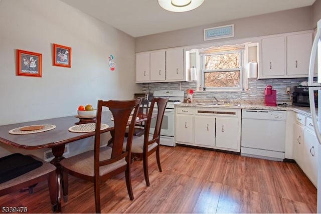 kitchen with white appliances, light wood-type flooring, white cabinets, and tasteful backsplash