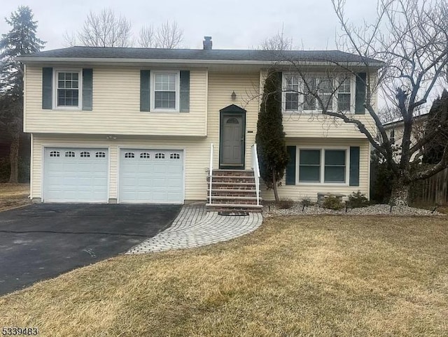 raised ranch featuring driveway, an attached garage, and a front yard